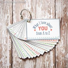 four tags with words on them are hanging from a wooden background that says, what i love about you from a to z