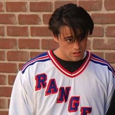 a young man in a baseball uniform holding a cell phone