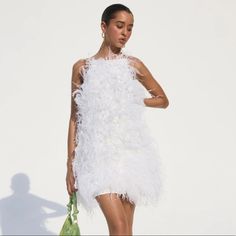 a woman in a white feather dress holding a green purse