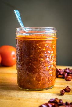 a glass jar filled with food sitting on top of a wooden table next to tomatoes