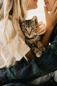 a woman holding a cat in her arms while looking at the camera man's face