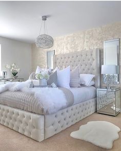 a large white bed sitting in a bedroom next to a dresser and mirror on the wall