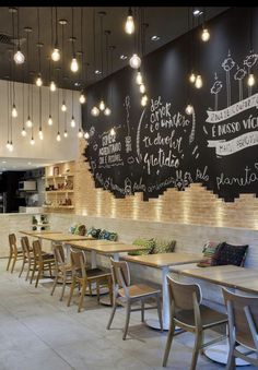 the interior of a restaurant with tables and chairs in front of a chalkboard wall