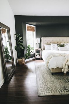 a bedroom with a bed, mirror and plants