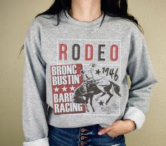 Rodeo Bronc Bustin Sweatshirt | Western graphic tee | Rodeo shirt | Western shirt | Cowboy tee | Cowgirl tshirt | Western gift | Rodeo gift .: Printed on Gildan 18000 crewneck sweatshirt .: 50% cotton, 50% polyester .: Medium-heavy fabric .: Loose fit .: Runs true to size (unisex fit) .: Made to order Trendy Short Sleeve Graphic Sweatshirt, Relaxed Fit Crew Neck Graphic Tee With Sublimation Design, Fan Apparel Short Sleeve Graphic Sweatshirt, Trendy Crew Neck Sublimation T-shirt With Screen Print, Crew Neck Graphic Tee For Rodeo, Trendy Cotton T-shirt For Rodeo, Cowgirl Tshirt, Western Style Cotton T-shirt For Rodeo, Rodeo Gifts