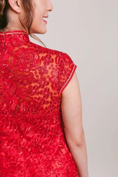 a woman wearing a red dress with an intricate lace pattern on the back and sides