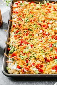 a casserole dish with broccoli, carrots and cheese on it