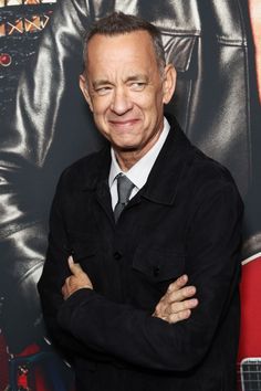 a man with his arms crossed standing in front of a movie poster