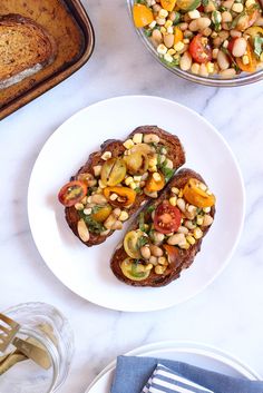 two pieces of toast with beans and vegetables on them