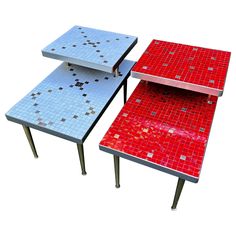 two red and blue tables sitting next to each other on top of metal legs,