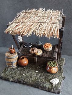 a small hut made out of wood and grass with food on the table next to it