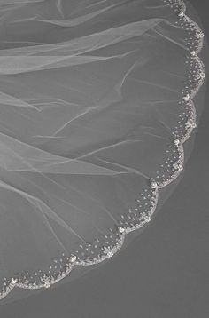 the bride's veil is draped over her wedding dress, which has beading on it