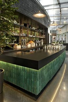 the interior of a restaurant with green and black counter tops, potted plants, and hanging lights