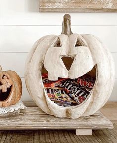 two carved pumpkins sitting on top of a wooden table next to each other with candy in them