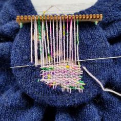 a close up of a blue piece of cloth with yarn on it and a needle in the middle