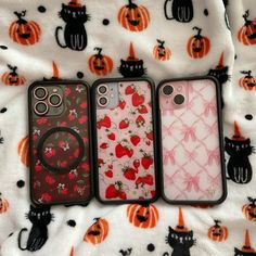 three cell phones sitting on top of a bed covered in pumpkins and other decorations