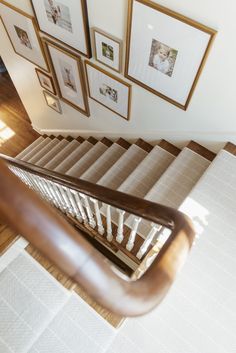 a stair case with pictures on the wall above it and below it is a wooden handrail