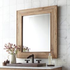 a bathroom sink with a mirror above it and flowers in vases on the counter