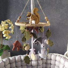 stuffed animals are hanging from a mobile in a room with gray walls and white pillows