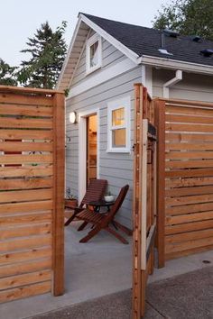 a small white house with a wooden fence around it's entrance and patio area