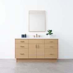 a bathroom vanity with two sinks and a mirror on the wall above it, in front of a white wall