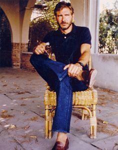 a man sitting on top of a wicker chair holding a wine bottle in his hand