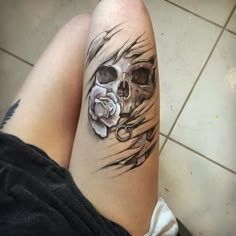 a woman's leg with a skull and rose tattoo on it