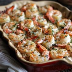 a casserole dish filled with shrimp and garnished with herbs