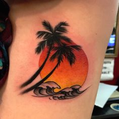 a woman's thigh with a sunset and palm tree tattoo on her left side