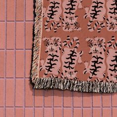 a brown and black rug with cats on it sitting on a pink tile floor next to a red brick wall