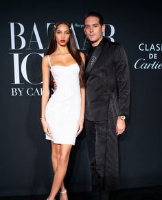 a man and woman standing next to each other in front of a black wall with the words baar too written on it