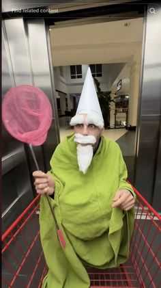 an old man in a green robe and white hat holding two pink lollipops