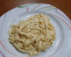 a white plate topped with macaroni and cheese on top of a wooden table