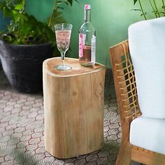 a wooden table with two wine glasses on it next to a chair and potted plant