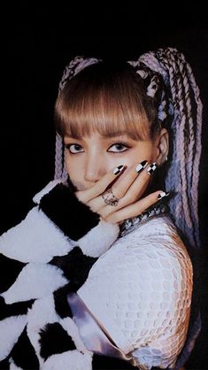 a woman with black and white nail polish holding her hands to her face while posing for the camera