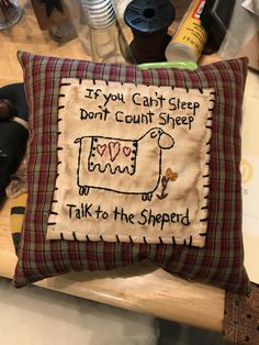 a pillow that is on top of a table with other items in the background and a cow saying, if you can't sleep don't count sheep