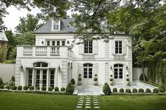 a large white house surrounded by lush green grass and trees in front of the building