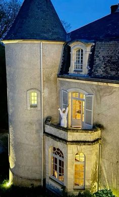 a person standing on the balcony of a house at night with their arms in the air