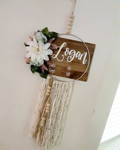 a wooden sign hanging from the side of a wall with flowers and beads on it