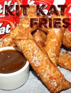 a pile of fried chicken sticks next to a cup of dipping sauce and two packets of kitkat