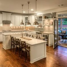 a large kitchen with white cabinets and wooden floors