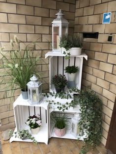 several white shelves with plants in them on the side of a brick wall next to a door