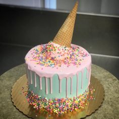 a birthday cake decorated with sprinkles and an ice cream cone on top