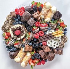 a platter filled with assorted chocolates, strawberries, raspberries and more