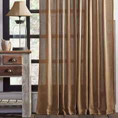 a living room with a lamp, table and window curtain in it's corner