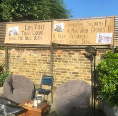 two chairs sitting next to each other in front of a brick wall with signs on it