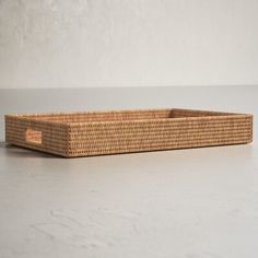 an empty wicker basket sitting on top of a white counter next to a wall