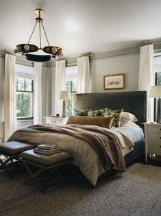 a bed sitting in a bedroom next to a window and a lamp hanging from the ceiling