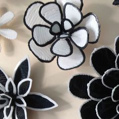 three paper flowers sitting on top of a table next to each other and one is black and white