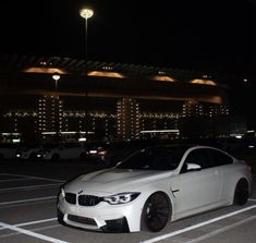 a white car parked in a parking lot at night with lights shining on the building